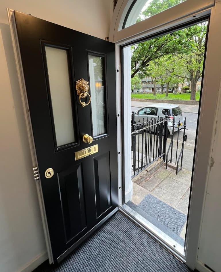 Black steel door with gold lion knocker shown open revealing interior
