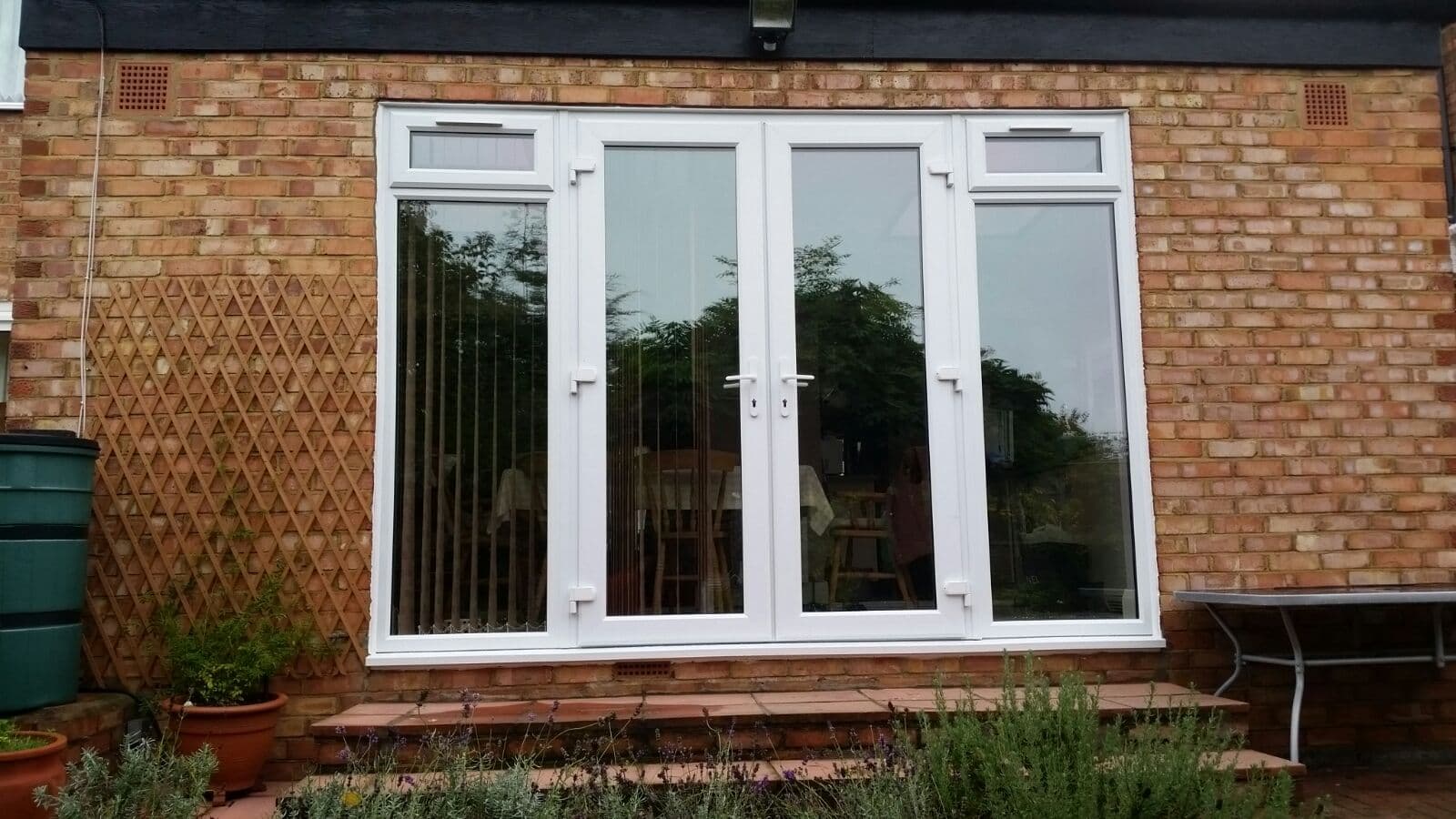 White uPVC patio doors opening to garden with potted plants